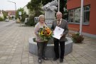 Erwin Reinwald hält die Urkunde. Neben ihm steht seine Frau mit Blumen.