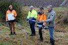 Vier Männer stehen an einem Bach in der Nähe von Oberndorf und schauen sich die Flächen darum herum an, ob an der Stelle Maßnahmen zum Schutz nach Unwettern Sinn machen. Sie haben auch eine Karte vom Gebiet dabei.