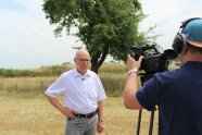 Der ehemalige Bürgermeister von Emskirchen Harald Kempe seht auf einem Feld vor einem Kamerateam.