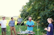 Männer und Frauen haben sich für ein Gruppenbild in Hechelbach auf dem Feld eines Bauern aufgestellt. Die Gäste aus Baden-Württemberg schauen sich die Bodenbewirtschaftung des Betriebs an.