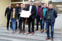 Sieben Männer und eine Frau haben sich zu einem Termin im Rathaus von Roßtal getroffen, um eine Urkunde zu übergeben.