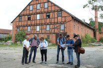 Ein Haus im Hintergrund, davor stehen Leute und besprechen die Sanierung.