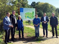 Mehrere Personen stehen vor einem Schild in der Natur