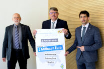 Drei Männer halten ein Schild in der Hand. Darauf ist unter anderem zu lesen, dass es für acht Kommunen in Mittelfranken über zwei Millionen Euro an EU-Fördermitteln gibt.
