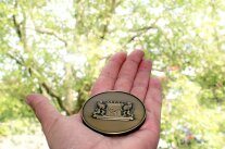 Eine Medaille liegt auf einer Hand und glänzt im morgendlichen Sonnenlicht.