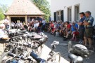 Menschen sitzen und stehen vor dem Pfarrhaus und hören den Ausführungen von Reinhold Kestler zu.