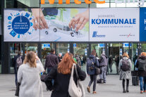 Besucher strömen zum Eingang der Messehalle mit dem Werbebanner „Kommunale“.